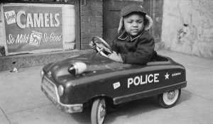 Charles "Teenie" Harris - Little boy driving toy police car on sidewalk, ca. 1938