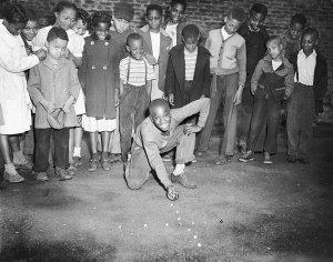 Charles "Teenie" Harris - 1948 City of Pittsburgh marbles champion Howard Hawkins, with children gathered behind him, 1948