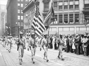 Charles "Teenie" Harris - Four color guard from 372nd Infantry marching in front of soldiers in parade, Fifth Avenue, Downtown Pittsburgh, 1942