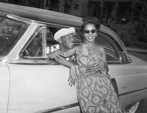 Charles "Teenie" Harris - Woman posed against Lincoln car, with man leaning out of driver's side, ca. 1952