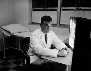 Charles "Teenie" Harris - Dr. Emile Nash seated before lit light boxes with x-rays, in Veterans Administration Hospital, Oakland, 1955