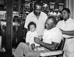 Charles "Teenie" Harris - Boxer "Jersey" Joe Walcott getting haircut from barber Clarence "Speedy" Williams, 1951