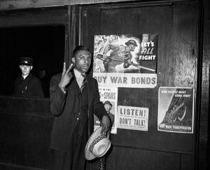 Charles "Teenie" Harris - Man making V sign outside railroad station, possibly for Double V campaign, ca. 1943